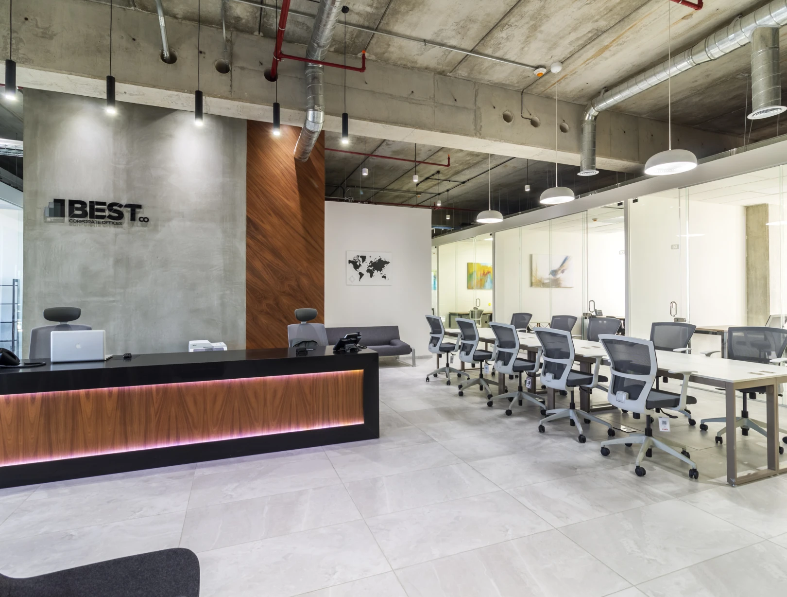 Recepción de oficinas BEST con mostrador de madera y mármol negro, y sala de juntas con sillas grises al fondo