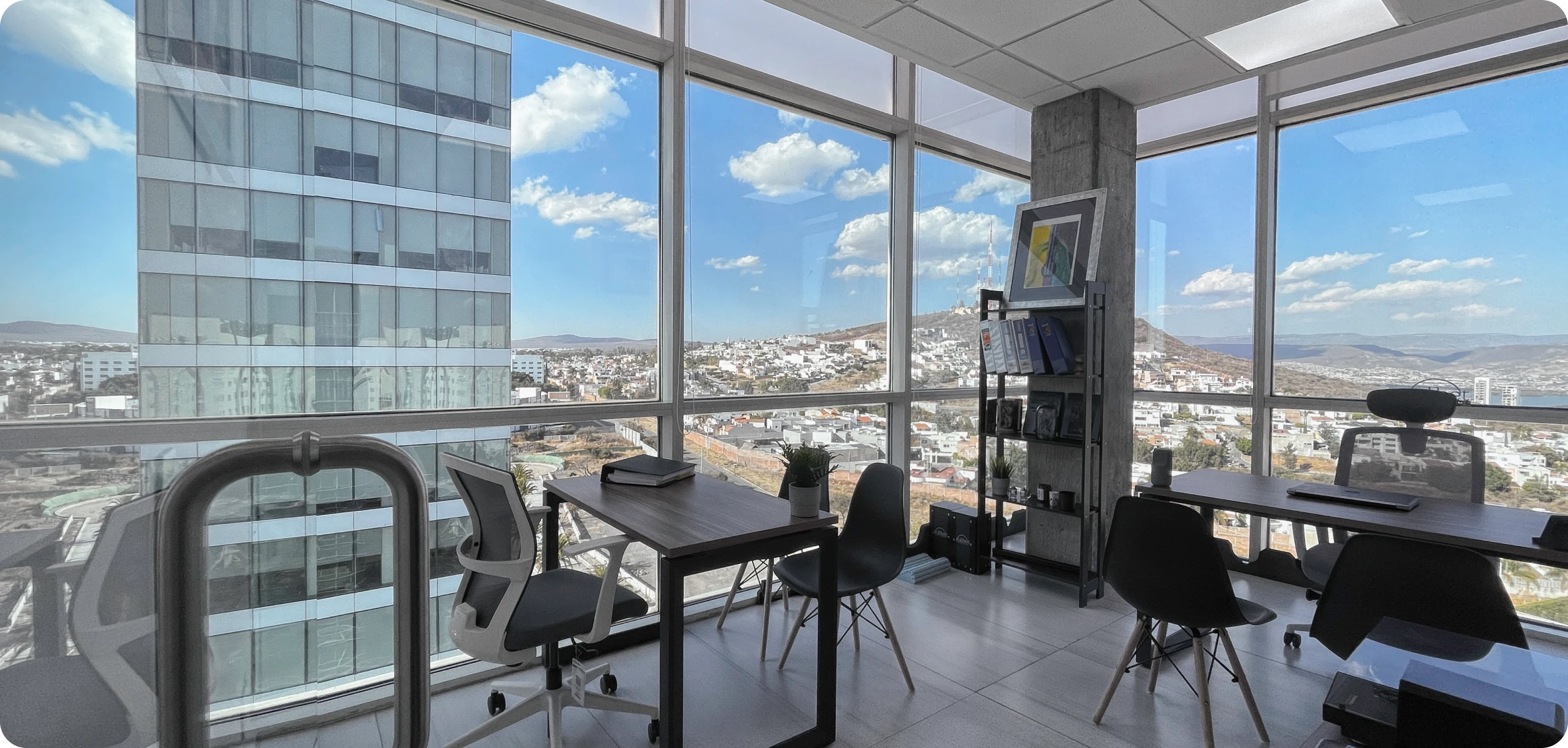 Fachada de la torre de oficinas de cristal azul rodeada de palmeras y áreas verdes bajo un cielo despejado